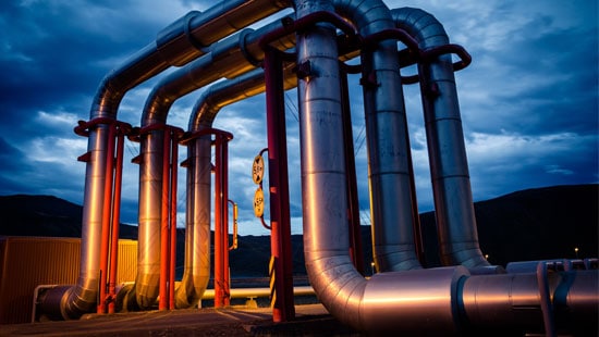 Cooling pipes flowing out of a geothermal power plant at sunset.
